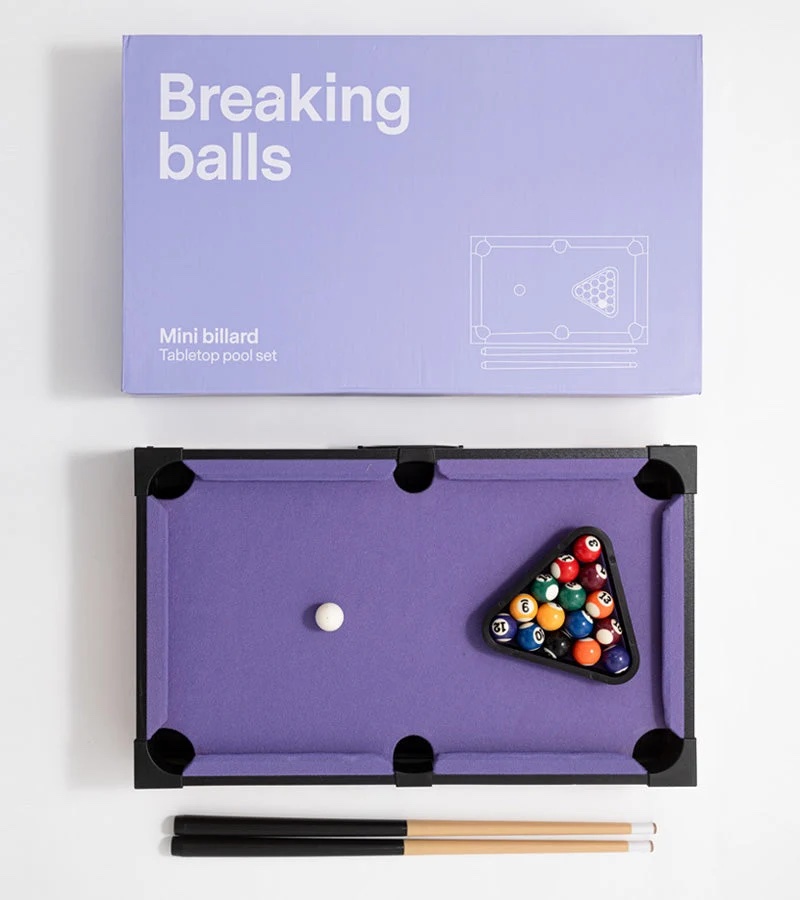 Mini billard de table au tapis lilas devant sa boîte