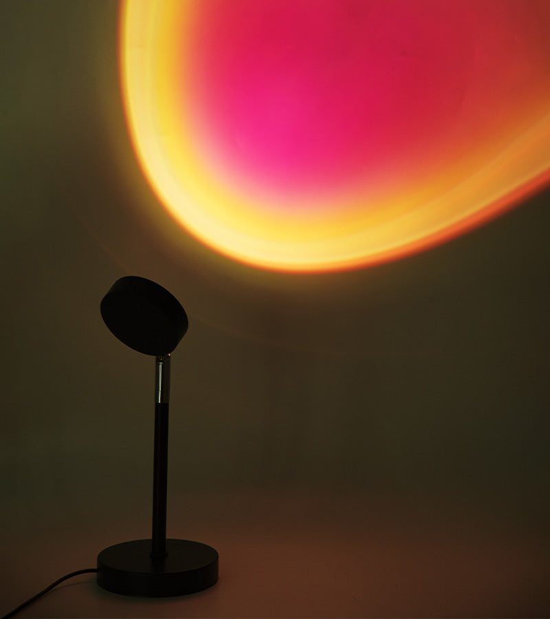 Lampe coucher de soleil projetant un halo orange et rose sur un mur
