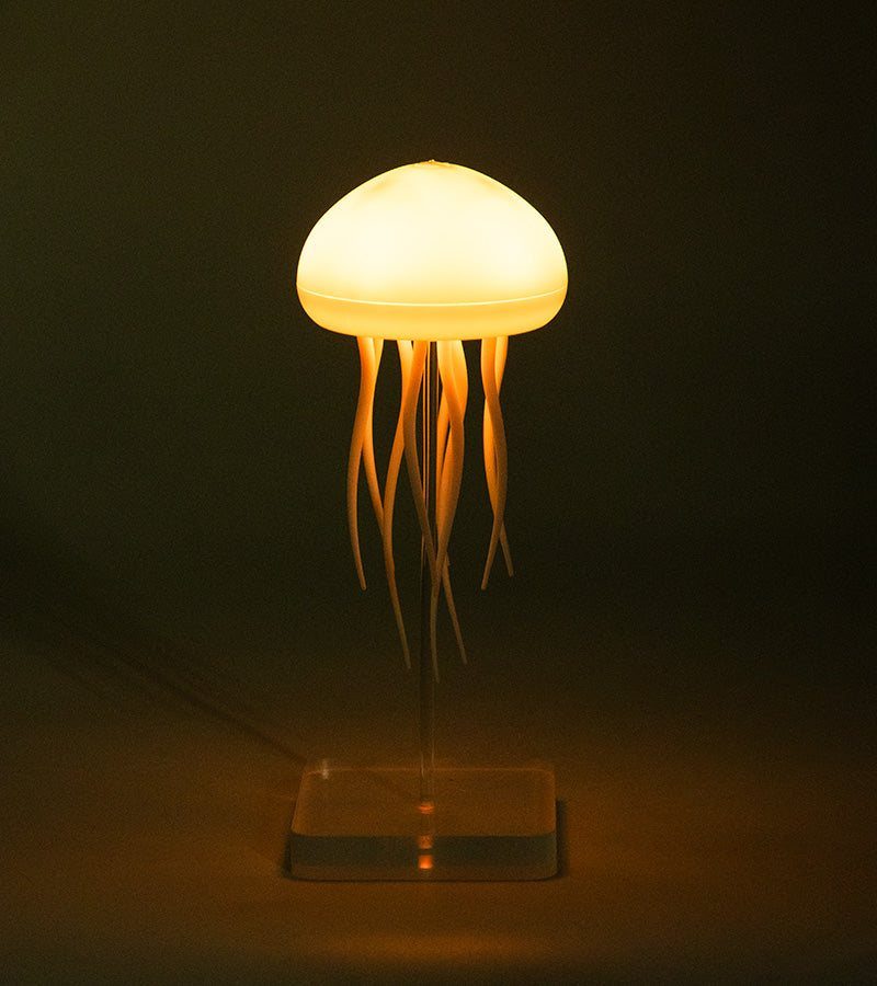 Veilleuse méduse flottante allumée d'une lumière chaude dans une pièce sombre
