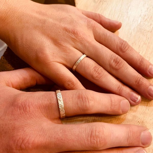 Mains d'un couple portant les alliances en argent fabriquées en atelier à Toulouse