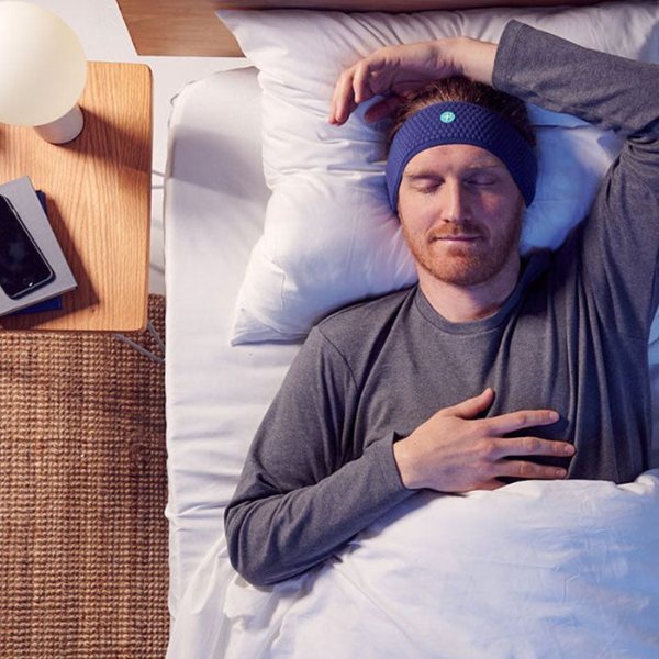 Homme allongé dans son lit portant un bandeau de sommeil Bluetooth bleu sur le front