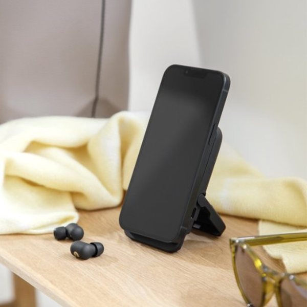 Batterie externe noire servant de support à un smartphone, avec deux écouteurs posés à côté