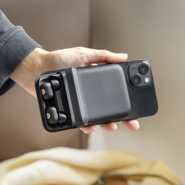 Main tenant un smartphone avec une batterie magnétique au dos contenant deux écouteurs sans fil
