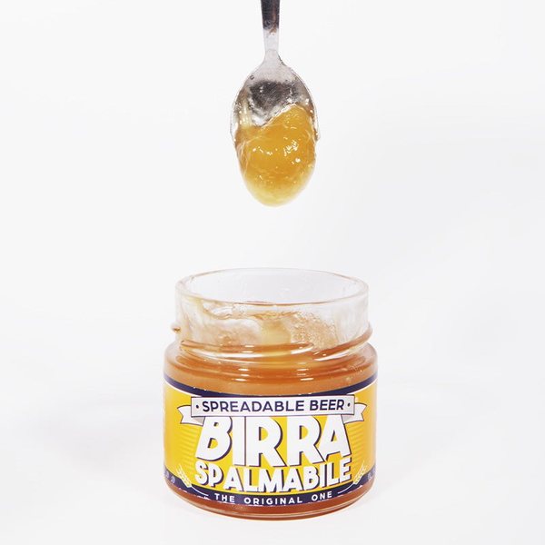 Pot de bière à tartiner Birra Spalmabile avec une cuillère qui laisse couler la pâte dorée