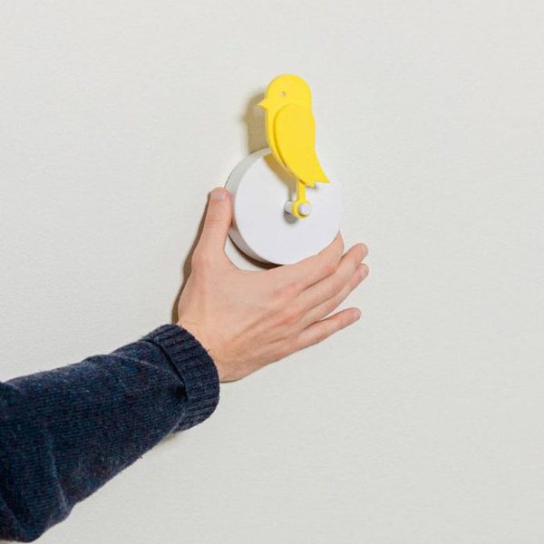 Capteur de CO2 Birdie en forme d'oiseau jaune fixé au mur, tenu par une main