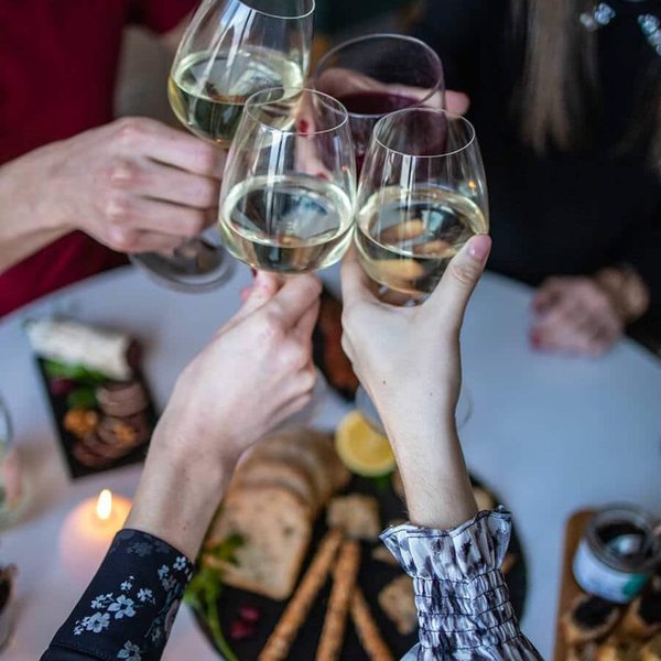 Amis qui trinquent avec des verres de vin blanc au-dessus d'une table d'apéritif garnie
