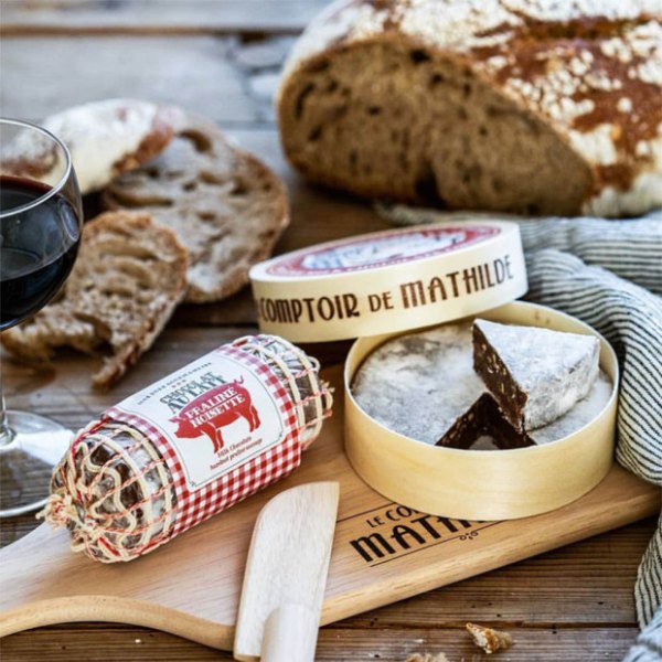 Saucisson et camembert en chocolat au lait sur une planche avec un couteau
