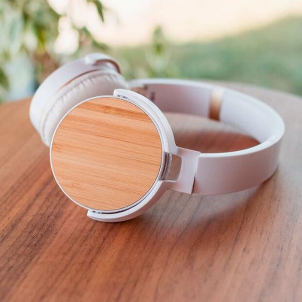 Casque Bluetooth blanc aux coques en bambou posé sur une table en bois