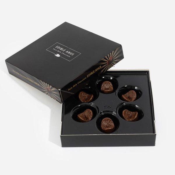 Boîte noire ouverte contenant six chocolats au lait en forme d'anus