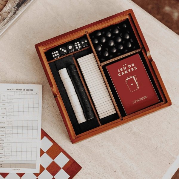 Coffret en bois ouvert contenant un jeu de cartes, des dés, des pions et une grille de score