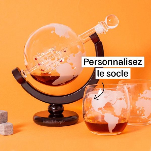 Carafe globe en verre remplie de whisky sur un socle en bois, avec un verre mappemonde sur fond orange