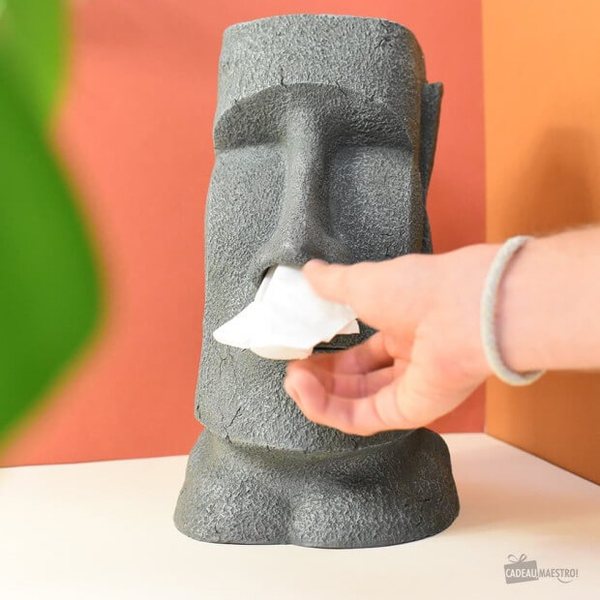 Main qui tire un mouchoir du nez d'un distributeur de mouchoirs en forme de statue Moaï grise