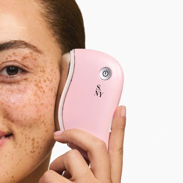 Femme se massant la pommette avec un gua sha LED rose Solaris