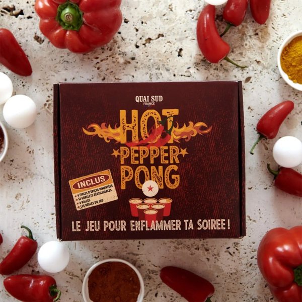 Coffret du jeu Hot Pepper Pong entouré de piments rouges, de balles de ping-pong et d'épices
