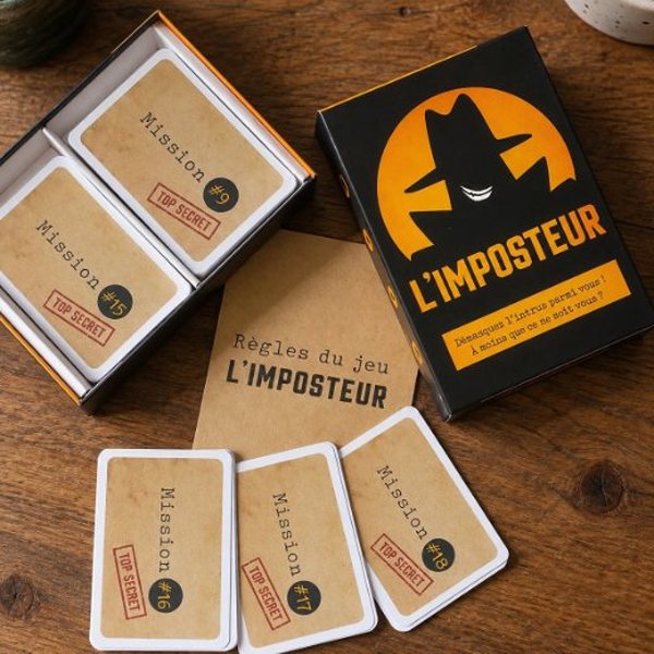 Boîte et cartes du jeu L'Imposteur posées sur une table en bois