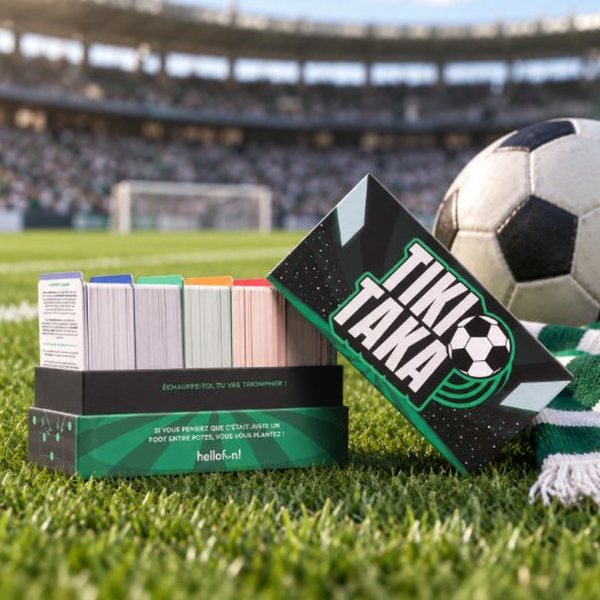 Boîte du jeu Tiki Taka posée sur une pelouse de stade avec un ballon de foot