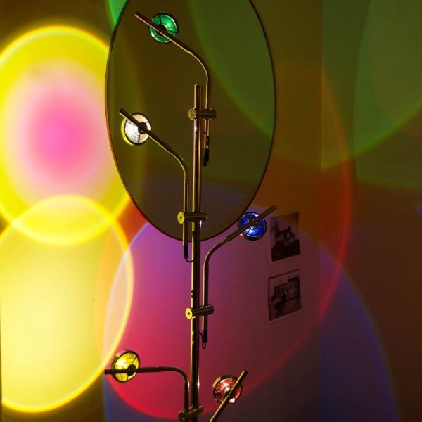 Lampadaire à 5 spots projetant des halos de couleurs coucher de soleil sur un mur avec miroir rond