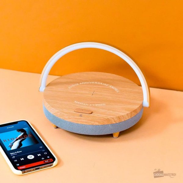 Lampe de chevet arceau blanc avec socle effet bois rechargeant un smartphone posé à côté
