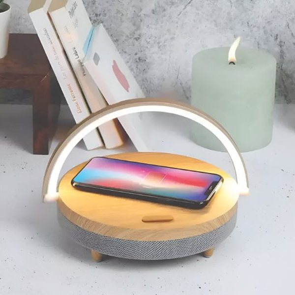 Lampe de chevet arceau au socle effet bois rechargeant un smartphone sur une table de nuit