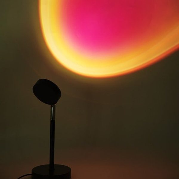 Lampe projetant un halo rouge et orange façon coucher de soleil sur un mur sombre