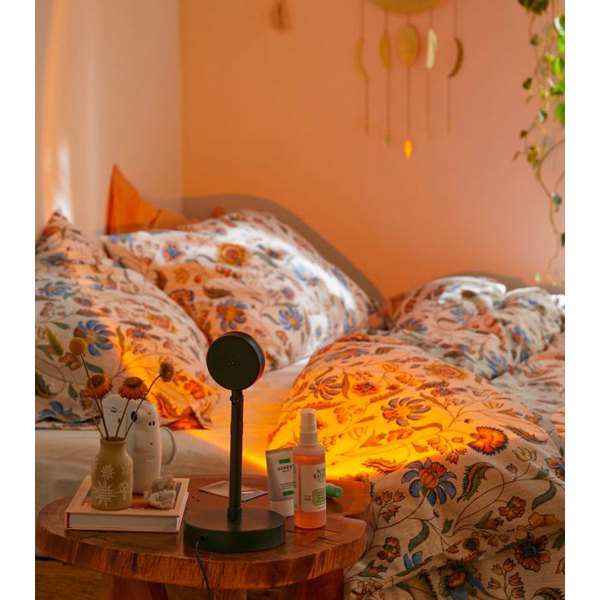 Lampe coucher de soleil projetant une lumière orangée sur un lit