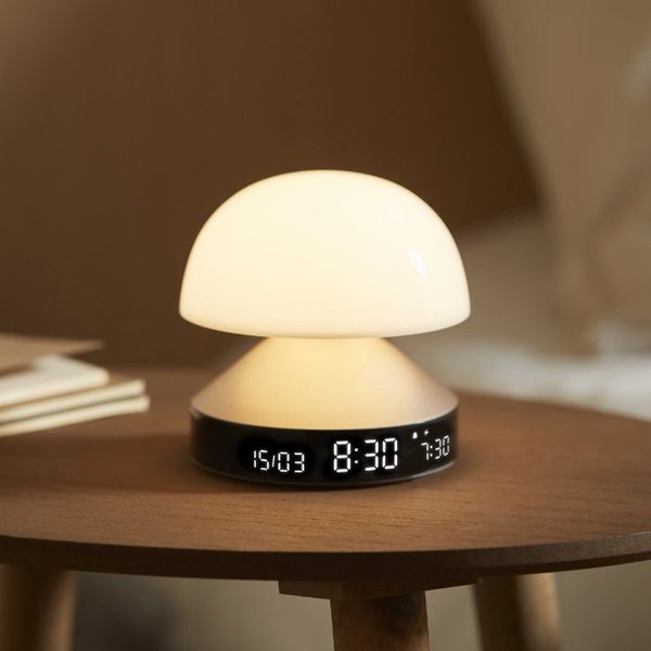 Lampe réveil champignon Mina Sunrise allumée sur une table de chevet en bois, écran affichant 8:30