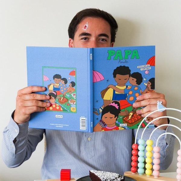 Homme lisant le livre de cuisine illustré Papa poule devant un boulier et un gâteau au chocolat