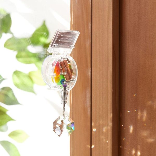 Attrape-soleil à cellule solaire et cristal suspendu à une fenêtre, projetant des reflets colorés