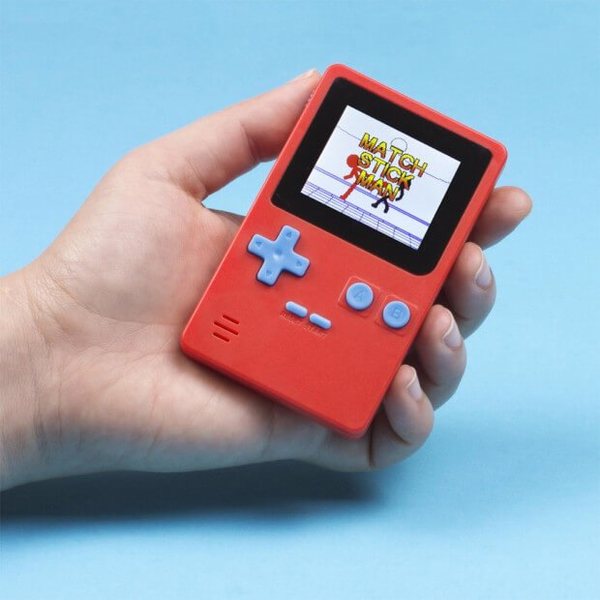 Main tenant une mini console portable rouge à écran couleur sur fond bleu