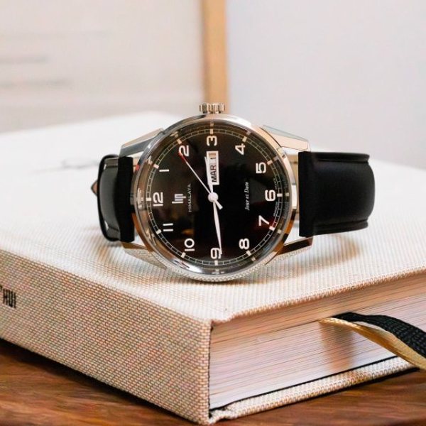 Montre LIP Himalaya au cadran noir et bracelet en cuir noir posée sur un livre