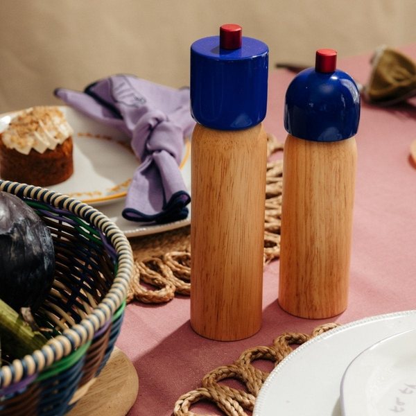 Deux moulins à sel et poivre en bois clair à tête bleue sur une table dressée