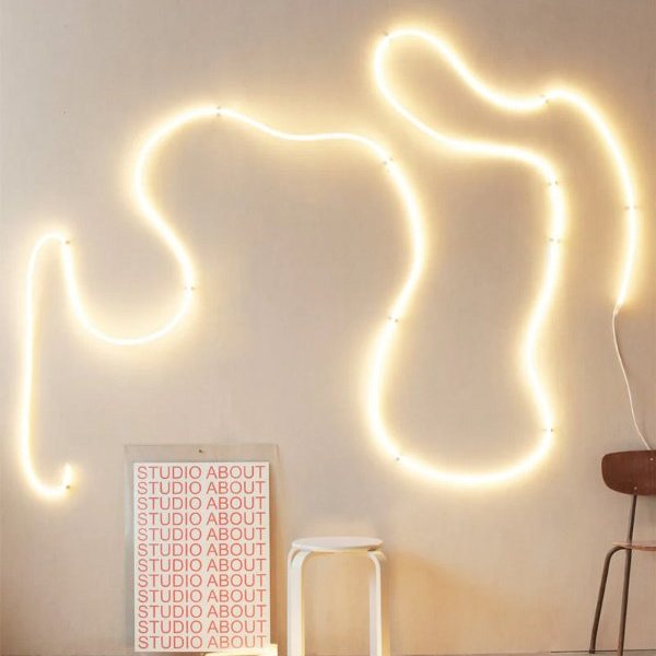 Néon flexible blanc chaud formant des courbes au mur d'une pièce lumineuse