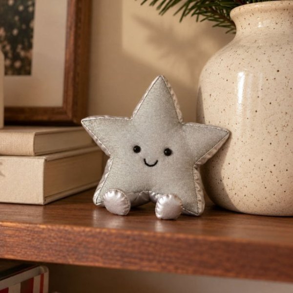 Peluche Jellycat en forme d'étoile argentée souriante posée sur une étagère