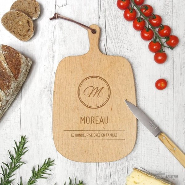 Planche à découper en bois gravée d'une initiale, du nom Moreau et d'une phrase, entourée de tomates cerises et de pain