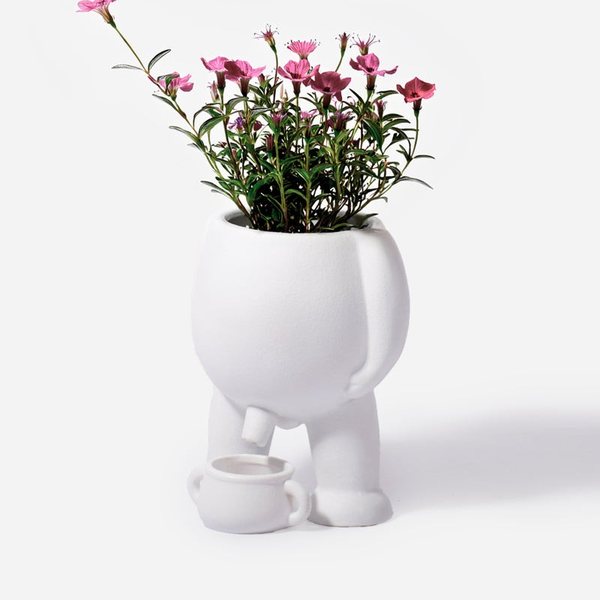 Pot à plante blanc en forme de petit bonhomme garni de fleurs roses, avec un mini pot à ses pieds