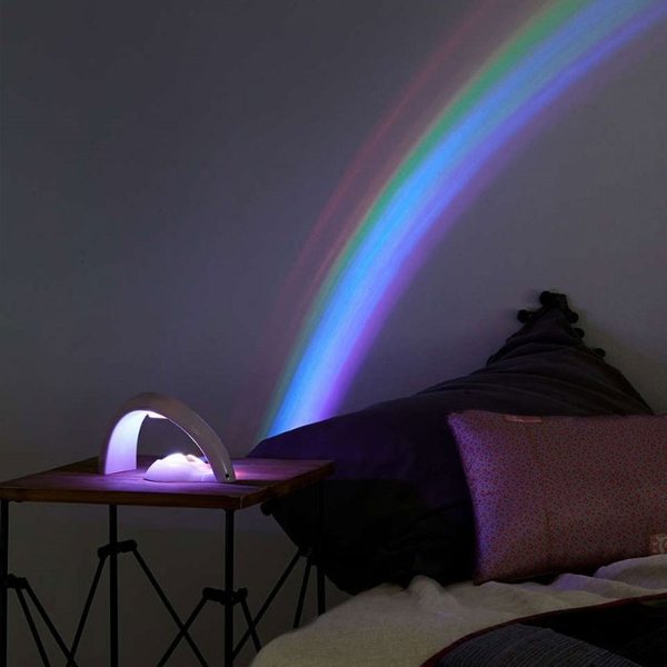 Projecteur blanc en arche diffusant un arc-en-ciel sur le mur d'une chambre dans la pénombre