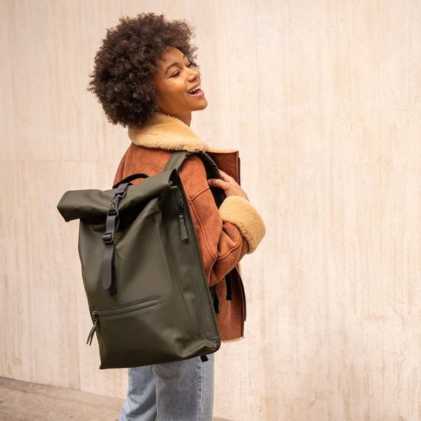 Jeune femme portant un sac à dos Rolltop Rains vert kaki à fermeture enroulable