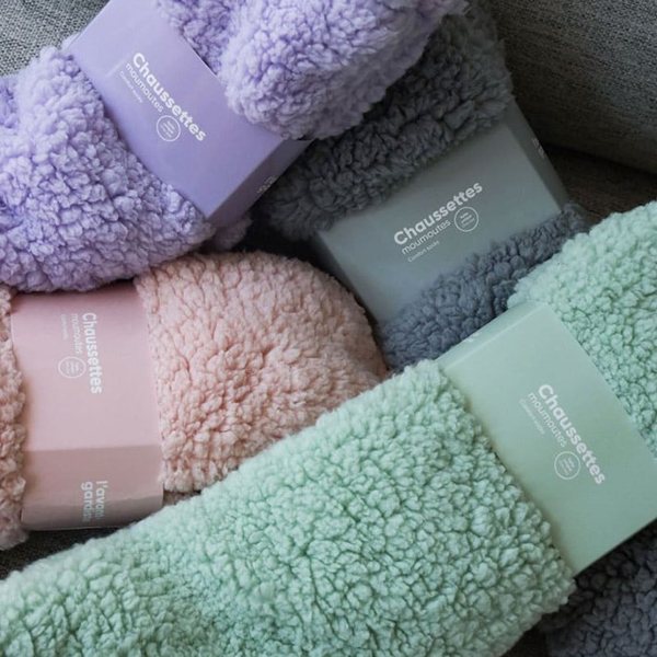 Chaussettes en moumoute lilas, grise, rose et verte roulées dans leur bande d'emballage