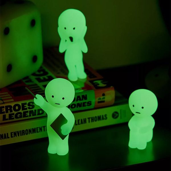 Trois figurines Smiski phosphorescentes qui brillent en vert dans le noir