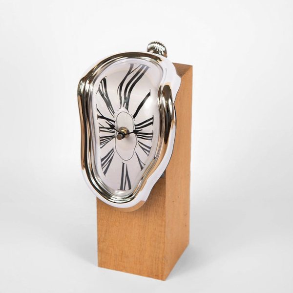 Horloge argentée qui semble fondre sur le bord d'un socle en bois, façon Dalí