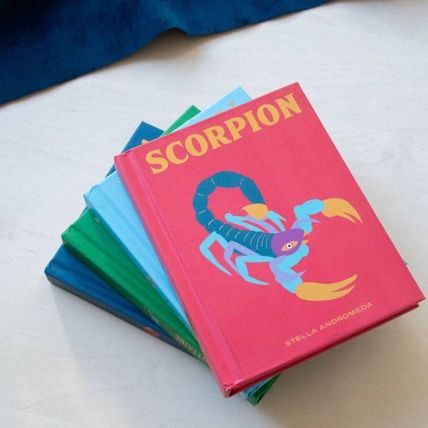 Pile de livres astrologiques colorés avec le livre Scorpion illustré sur le dessus