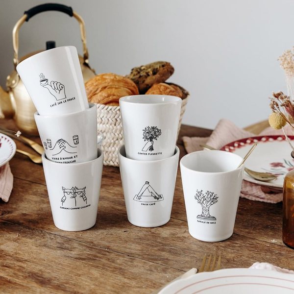 Mugs blancs illustrés d'expressions françaises sur une table de petit-déjeuner