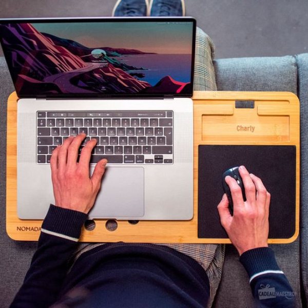 Personne travaillant sur un ordinateur portable posé sur un support en bambou avec tapis de souris intégré
