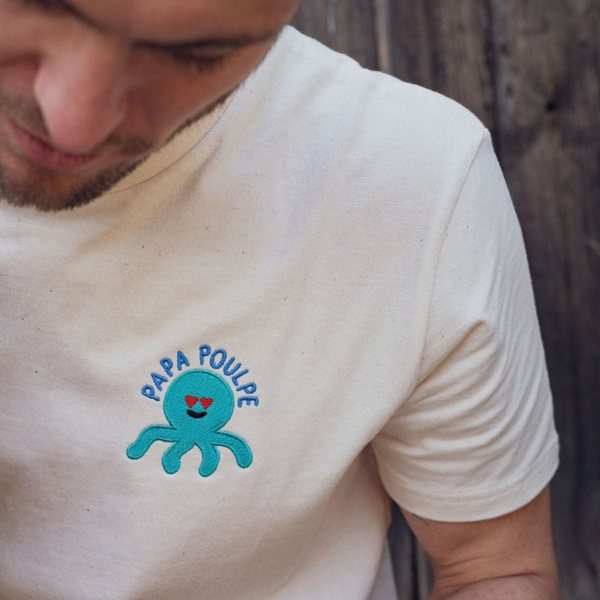 Homme portant un t-shirt blanc brodé d'un petit poulpe bleu et de l'inscription Papa Poulpe