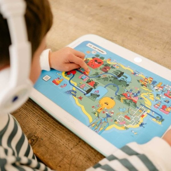 Enfant explorant un livre posé sur la tablette interactive sans écran Bugali