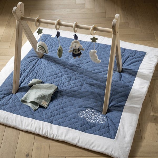 Grand tapis matelassé bleu brodé d'un nuage, sous une arche d'éveil en bois, sur un parquet