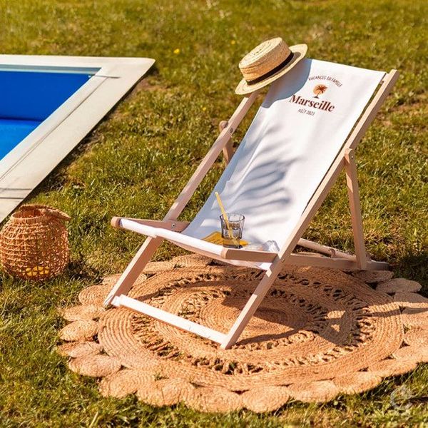Transat en bois de hêtre à toile blanche imprimée « Marseille » posé sur l'herbe au bord d'une piscine