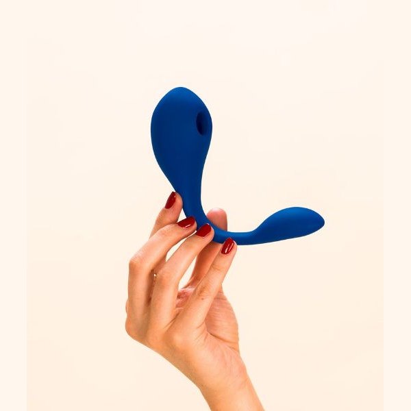 Main tenant le vibromasseur Coco bleu de Puissante sur fond crème